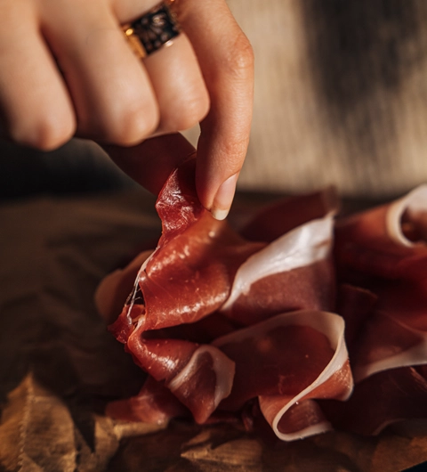 Doigts d'une femme attrape une tranche de jambon de Bayonne