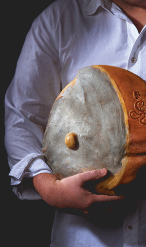 Homme salaisonnier porte un jambon de Bayonne