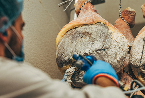 Homme appliquant le pannage sur le jambon de Bayonne